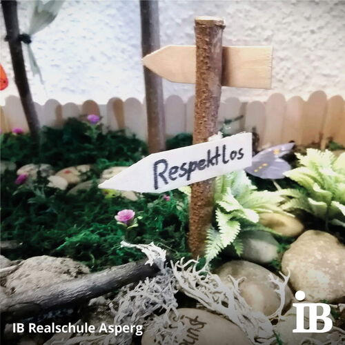 Ein Miniaturschild mit der Aufschrift "RespektLos" steht in einem dekorativen Gartenmodell der Realschule Asperg.