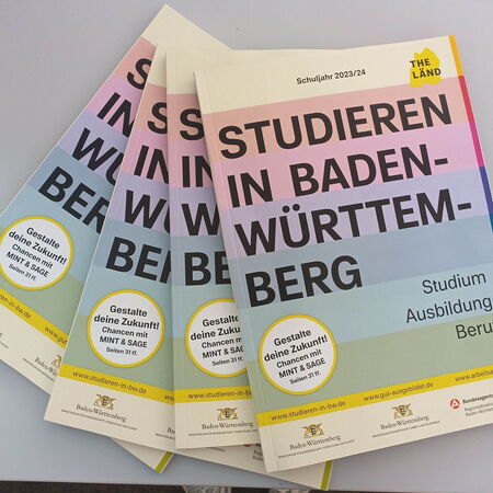 Mehrere Broschüren mit dem Titel "Studieren in Baden-Württemberg" liegen auf einem Tisch, um Bildungsoptionen zu präsentieren.