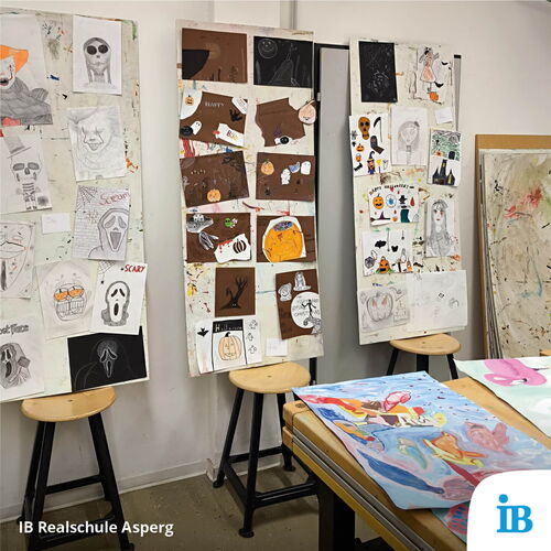 Bunte Zeichnungen und Collagen mit Halloween-Motiven sind auf Staffeleien in einem Kunstklassenzimmer der IB Realschule Asperg ausgestellt.