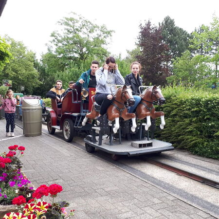 Eine Gruppe von Menschen genießt eine Fahrt in einer Kutsche auf Schienen, umgeben von grüner Natur.