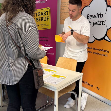 Ein Mann informiert eine Frau an einem Stand über Ausbildungsmöglichkeiten in Stuttgart.