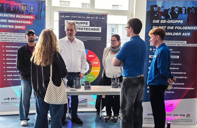 Eine Gruppe von Personen diskutiert am Stand der EB-Gruppe über Ausbildungs- und Karrieremöglichkeiten in der Elektrotechnik.