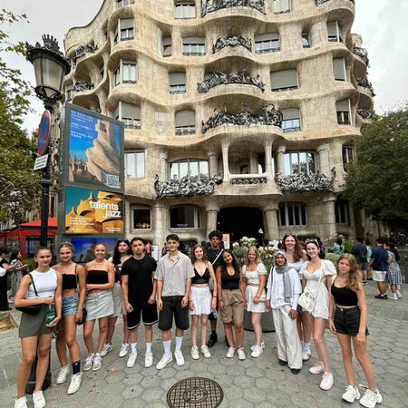 Eine Gruppe junger Menschen posiert vor dem wellenförmigen Gebäude Casa Milà in Barcelona.