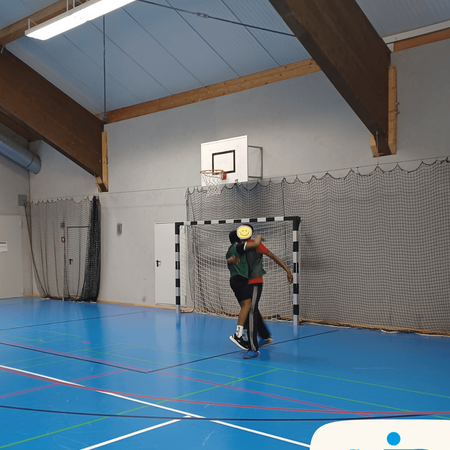 Zwei Spieler feiern ein Tor während eines spannenden Fußballturniers in einer Sporthalle.