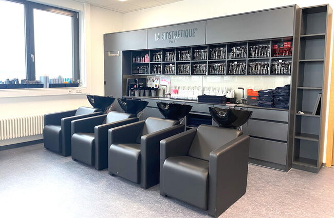Ein moderner Friseursalon mit eleganten Waschbecken und einem Sortiment an Pflegeprodukten im Hintergrund.