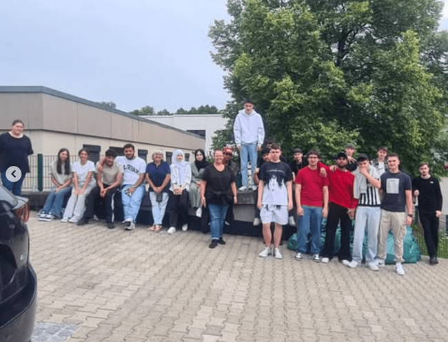 Eine Gruppe von Schülern und Lehrern posiert fröhlich gemeinsam vor einem Gebäude während des Projekttags.
