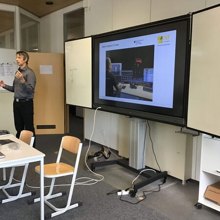 Ein Mann hält einen Vortrag in einem Büro, während auf dem Bildschirm eine Präsentation über Motion Capture angezeigt wird.