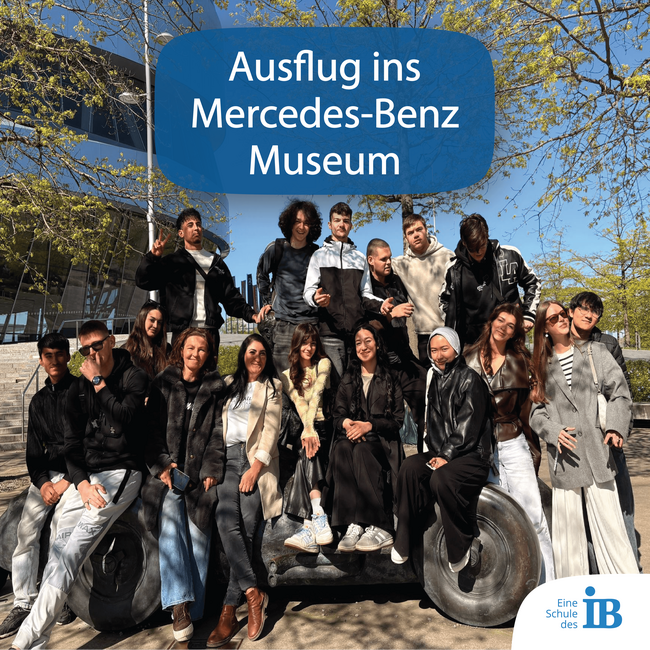Eine Gruppe von Jugendlichen posiert fröhlich auf einem Kunstwerk vor dem Mercedes-Benz Museum während ihres Ausflugs.