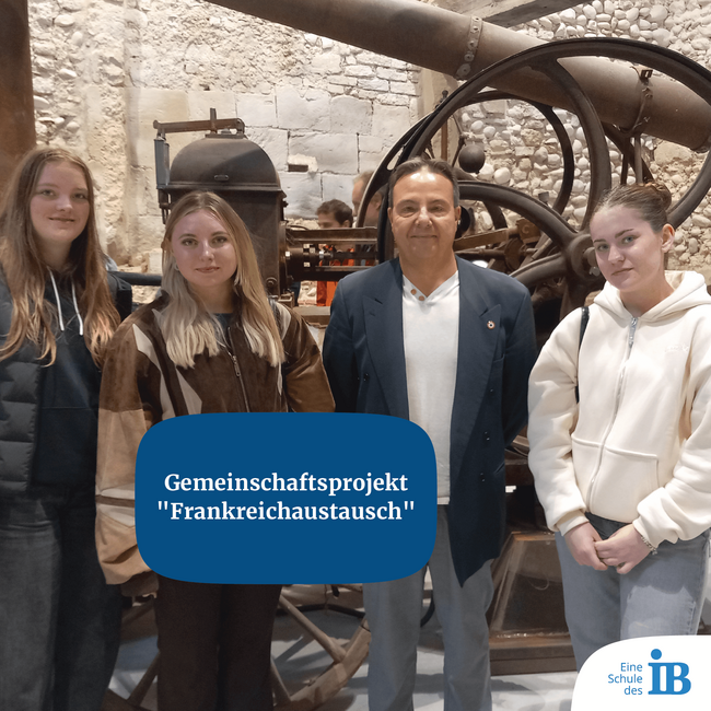 Vier Personen posieren vor einer historischen Maschine für das Gemeinschaftsprojekt "Frankreichaustausch".