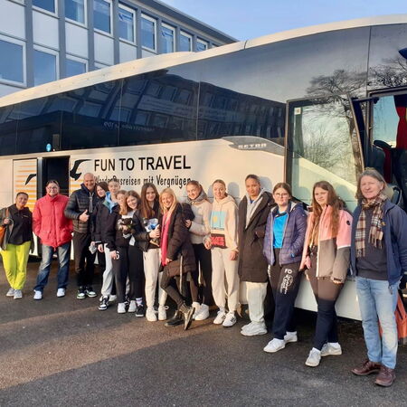 Schüler:innen vor einem Reisebus, kurz vor der Abfahrt