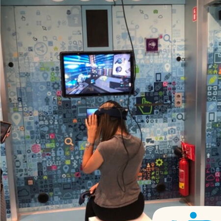 Eine Person testet Virtual Reality in einem modernen, technologieorientierten Raum mit buntem Hintergrund. | © IB