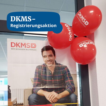 Ein DKMS-Plakat mit einem lächelnden Mann wird von roten Ballons begleitet, die eine Registrierungsaktion ankündigen.