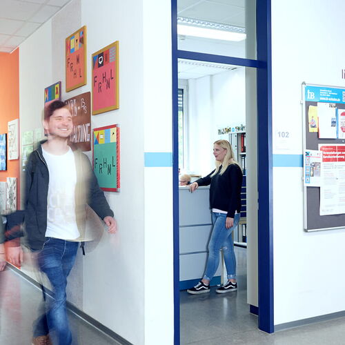 Schüler läuft im Flur an einem Klassenzimmer vorbei