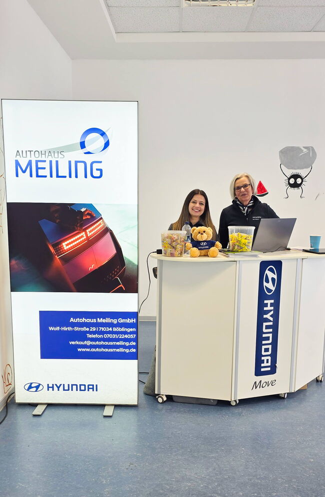Im Autohaus Meiling in Böblingen begrüßen zwei Damen die Kunden an einem Empfangstresen mit Hyundai-Werbung.