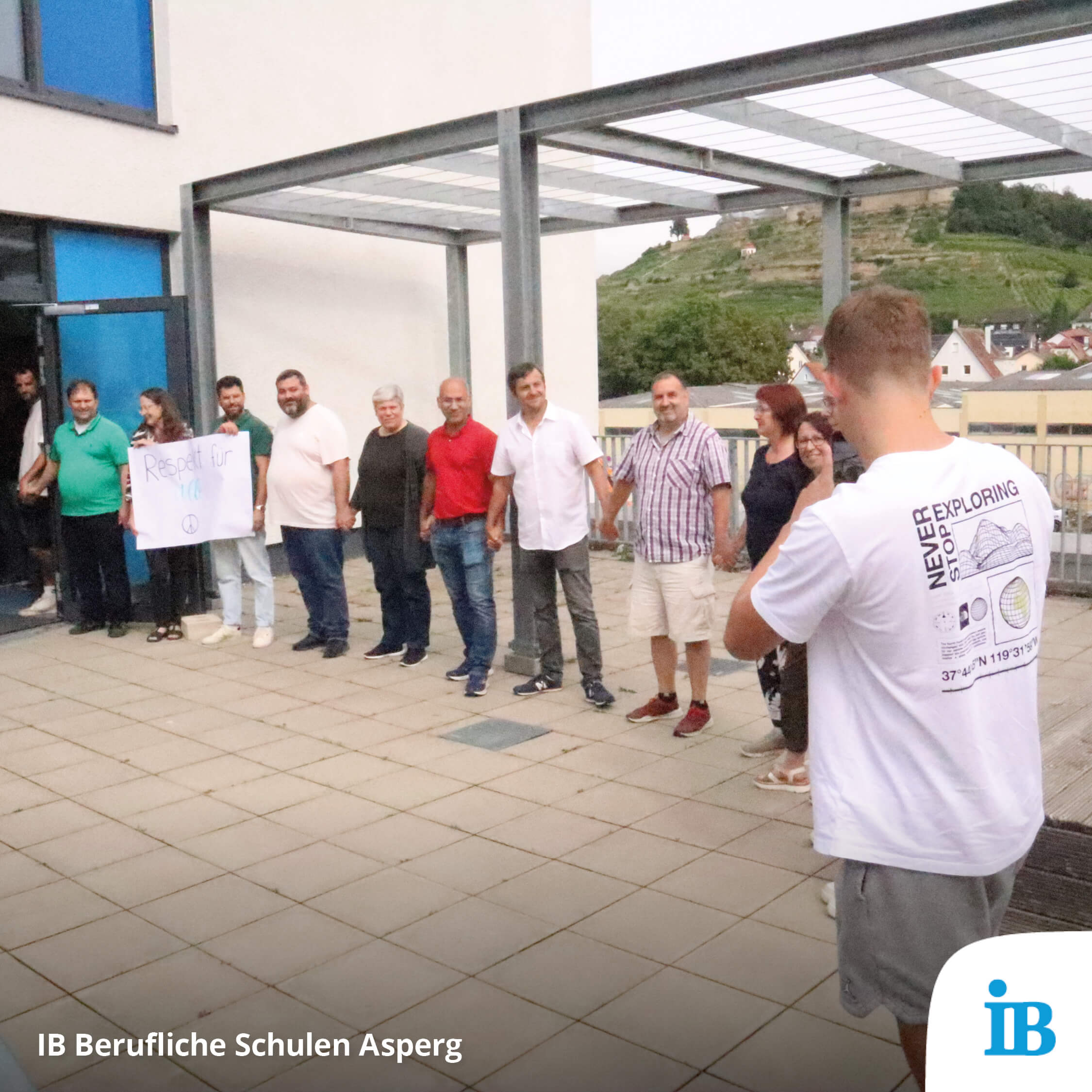 Eine Gruppe von Menschen hält sich an den Händen, während sie draußen ein Schild mit der Aufschrift "Respekt für alle" zeigen.