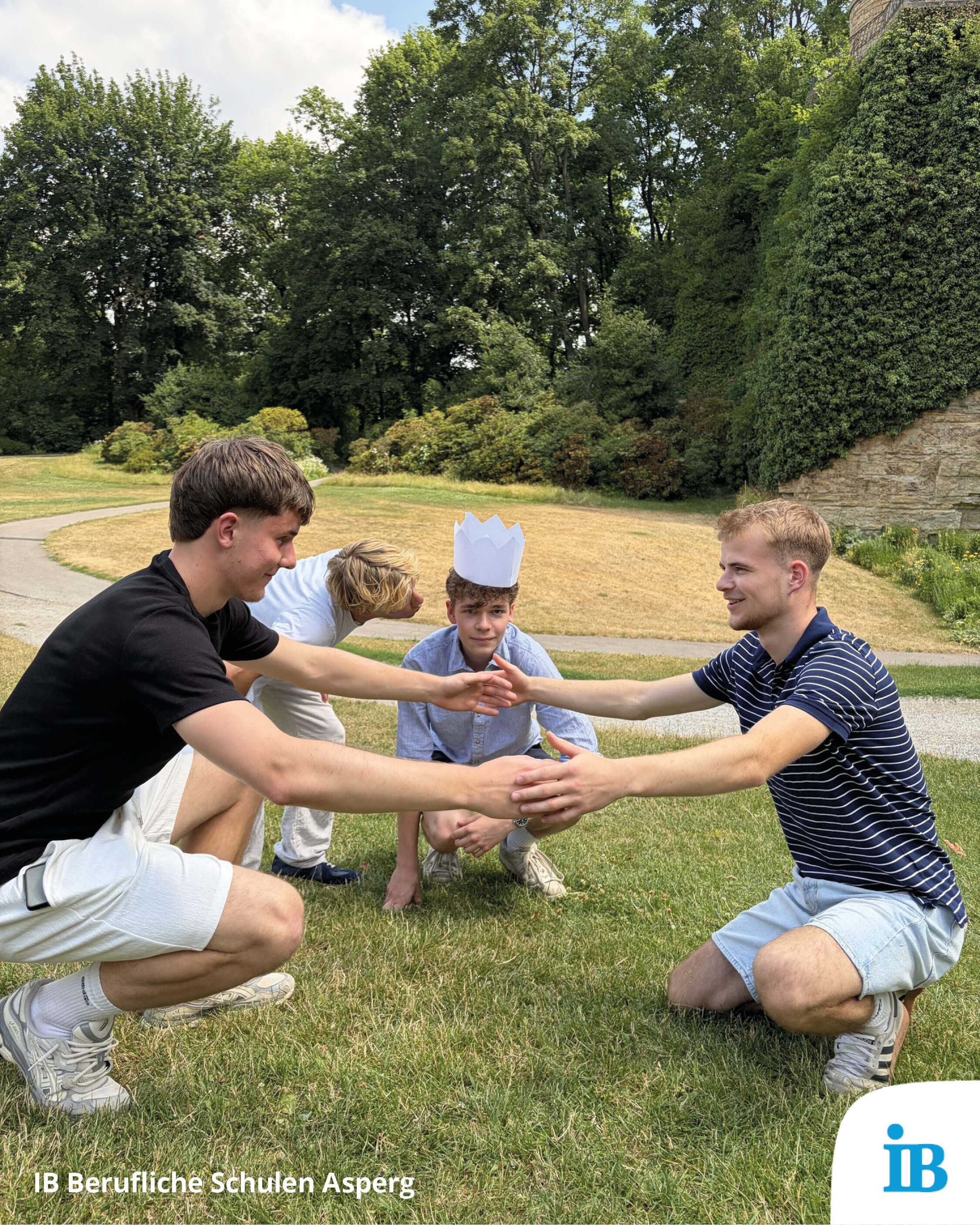 Eine Gruppe von Jugendlichen spielt ein Spiel im Freien, während einer einen Papierhut trägt. | © IB Berufliche Schulen Asperg
