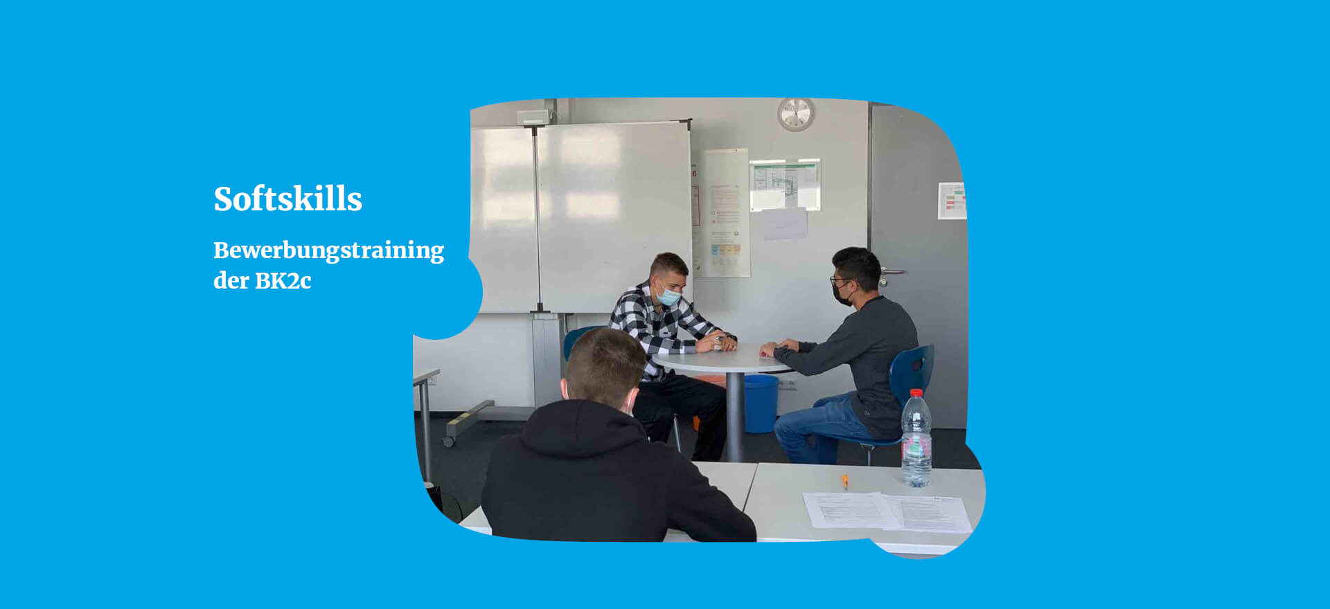 In einem Klassenzimmer üben drei Personen Bewerbungsgespräche, um ihre Softskills zu verbessern.