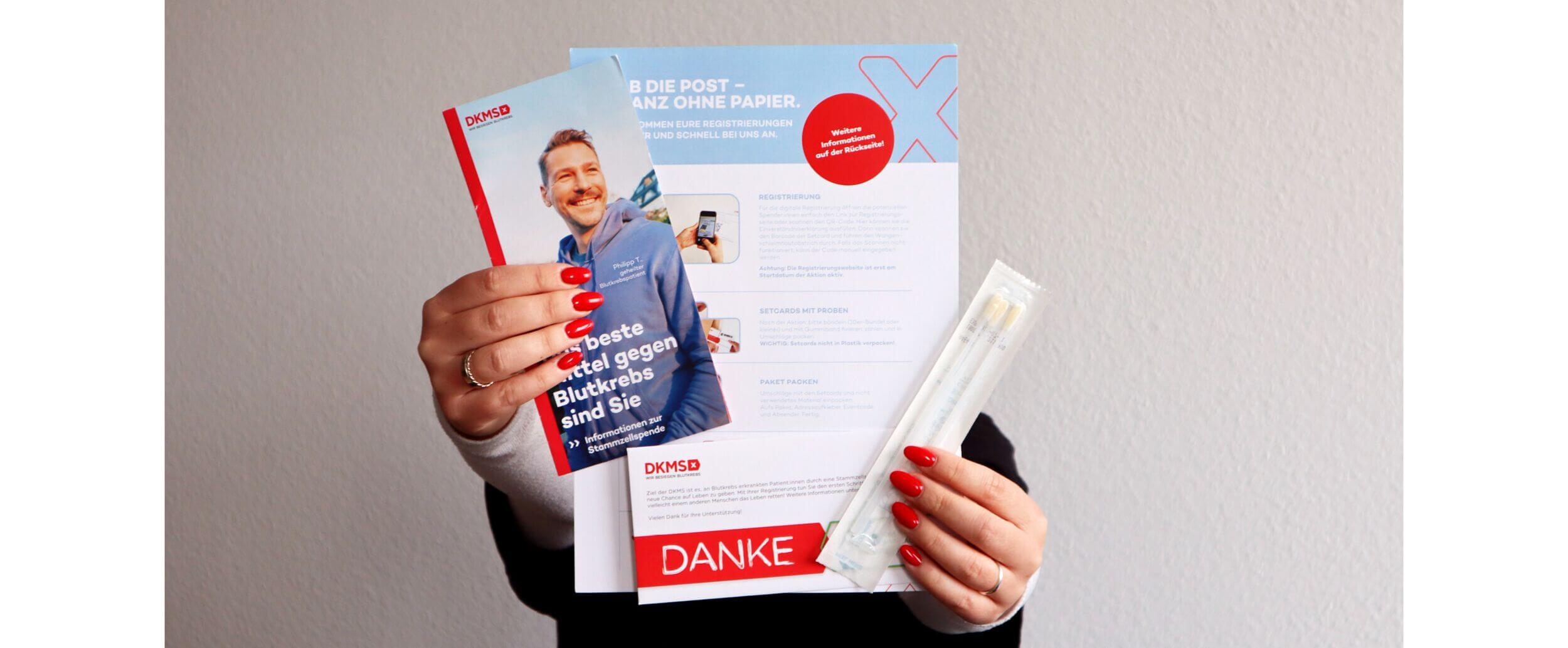 Eine Person hält DKMS-Informationsmaterialien und ein Testset zum Thema Blutkrebs in den Händen.