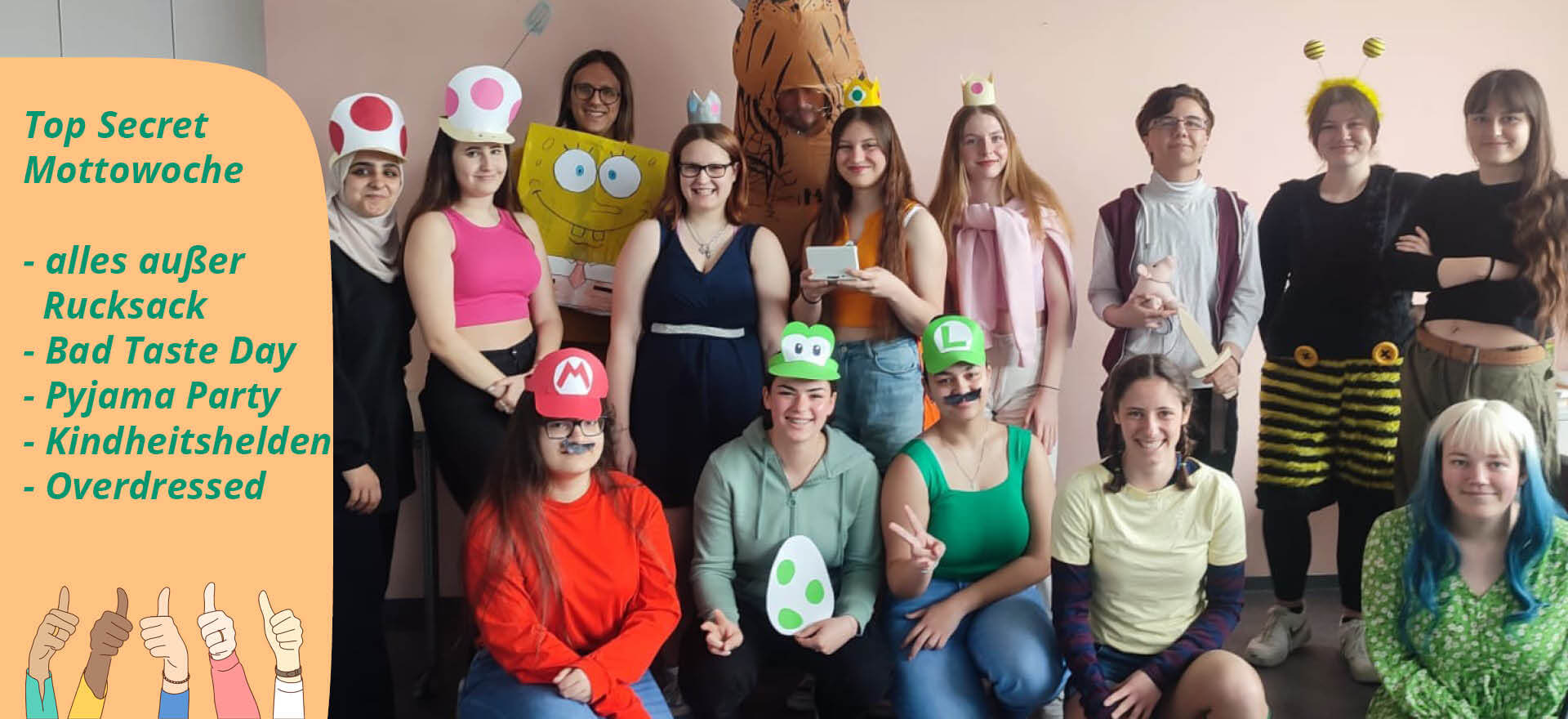 Eine Gruppe von Menschen in kreativen Kostümen posiert fröhlich für die "Top Secret Mottowoche" vor einer Wand.