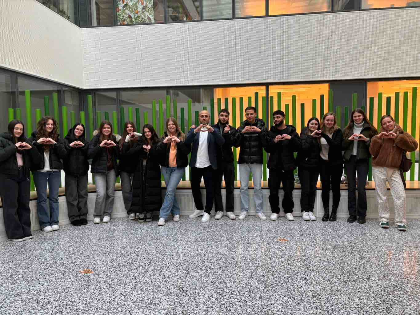 Eine Gruppe von Menschen steht in einem Gebäude und formt mit ihren Händen ein Herz.