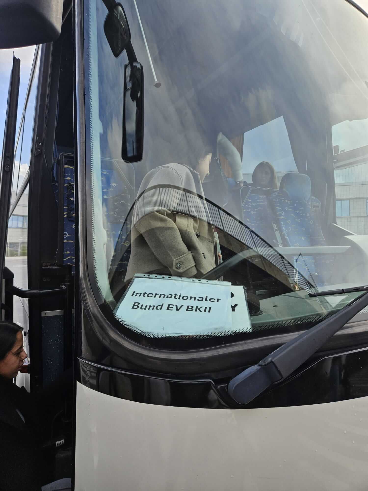 Ein Bus mit einem Schild des Internationalen Bund EV BKII steht bereit, während Passagiere einsteigen.