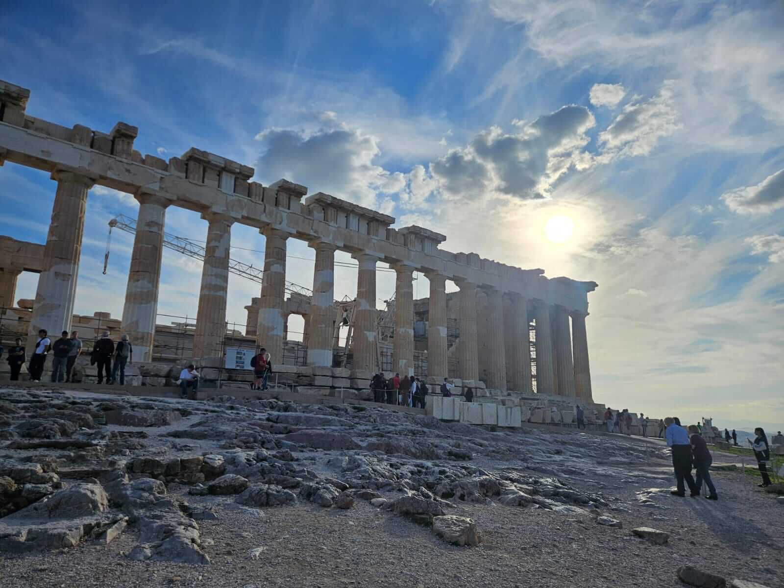 Menschen erkunden den Parthenon bei strahlendem Sonnenschein und bewundern die antike Architektur.