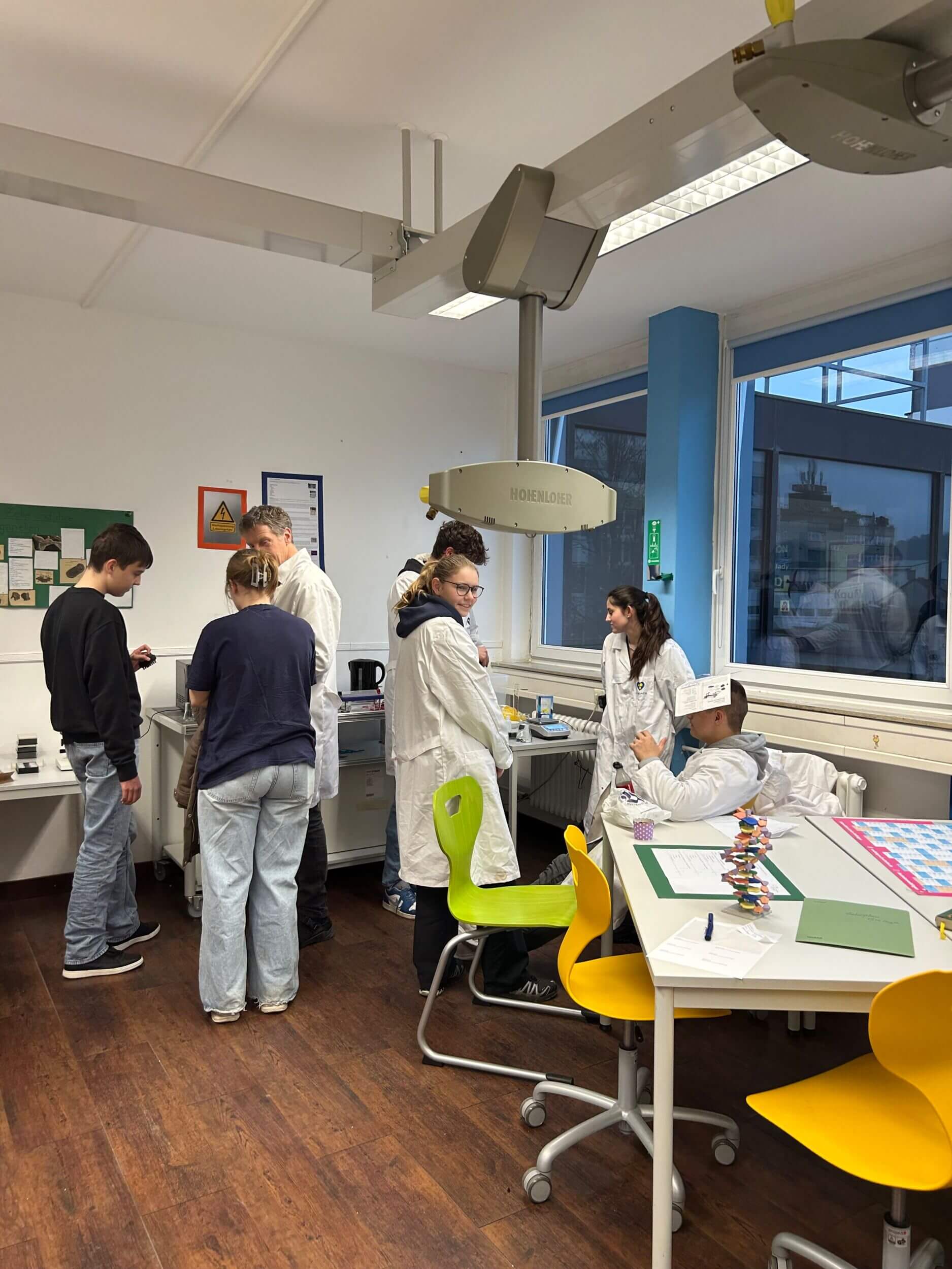 Schüler in weißen Kitteln experimentieren in einem modernen Labor mit wissenschaftlichen Werkzeugen und Modellen.