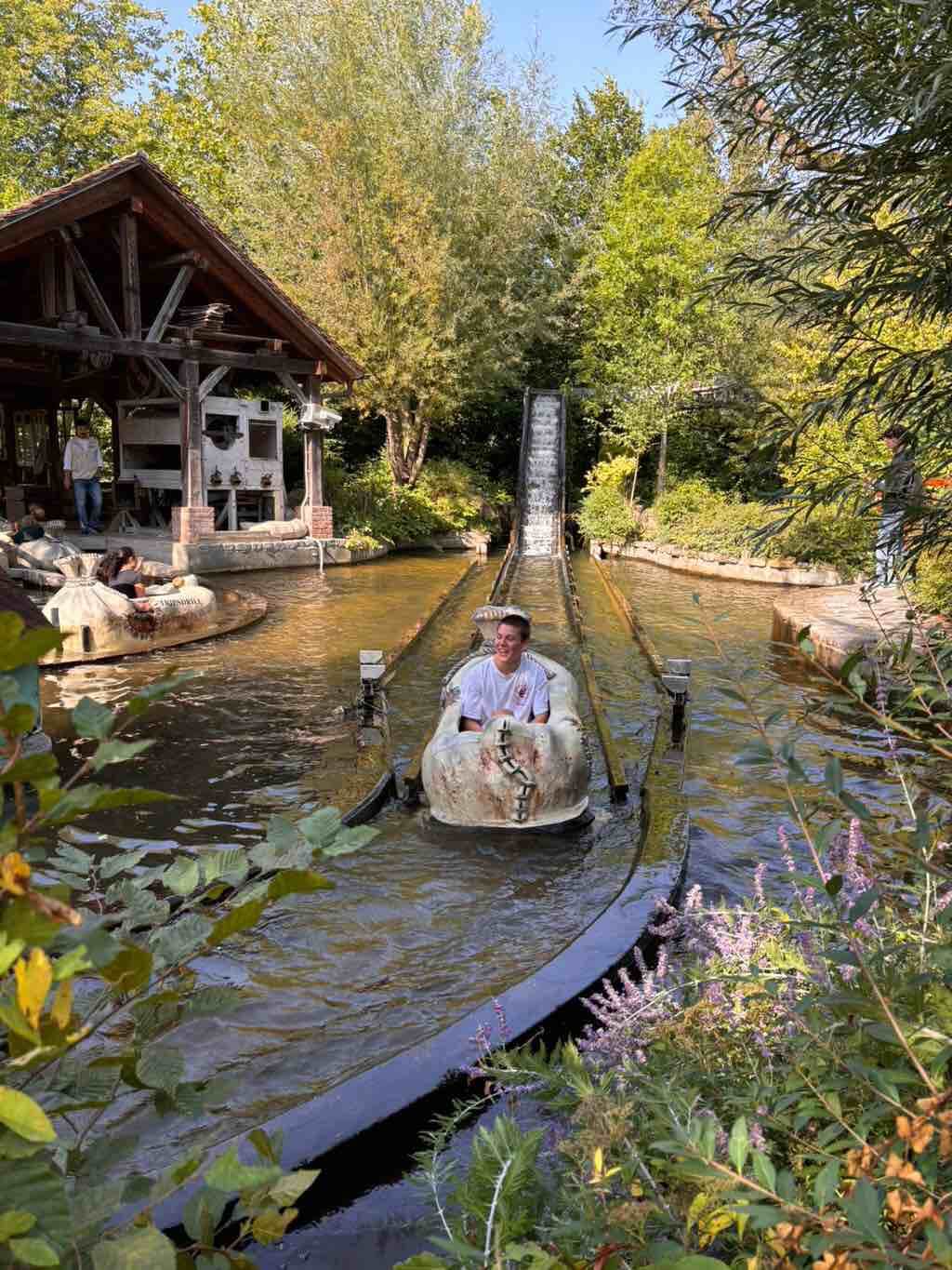 Ein Mann genießt eine Fahrt in einem Baumstammboot auf einer Wasserbahn inmitten üppiger Vegetation.