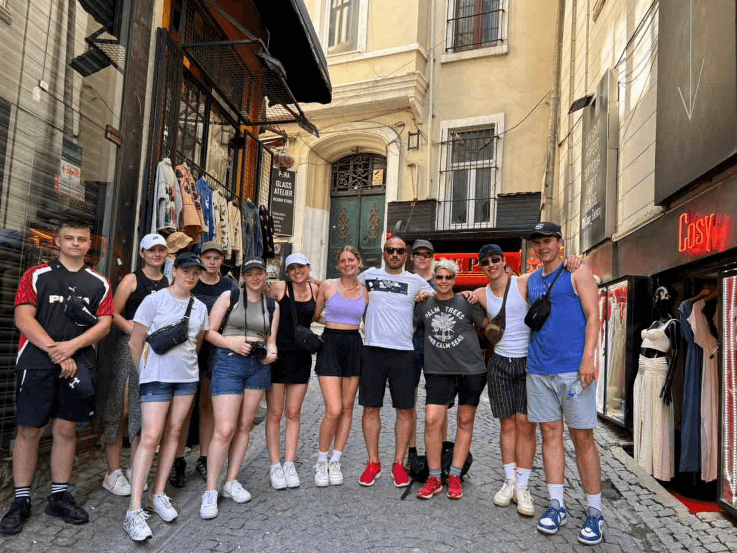 Eine Gruppe von Menschen posiert lächelnd in einer belebten Einkaufsstraße vor historischen Gebäuden.